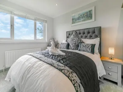 a bedroom with a large bed and two windows at The Lodge in Helston