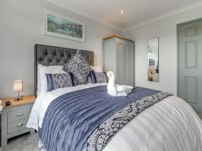 a bedroom with a bed with a white dog sitting on it at The Lodge in Helston