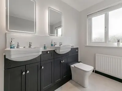 a bathroom with two sinks and a toilet and a mirror at The Lodge in Helston