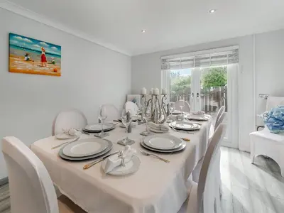 a white dining room with a white table and chairs at The Lodge in Helston