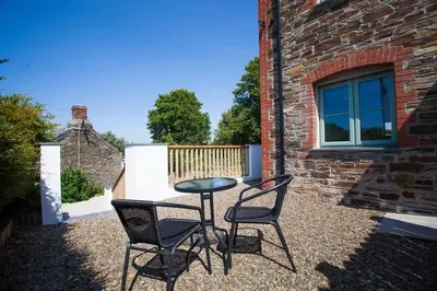 two chairs and a table in front of a brick building at Rumford Heights guest apartment in Saint Ervan