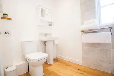 a white bathroom with a toilet and a sink at Rumford Heights guest apartment in Saint Ervan