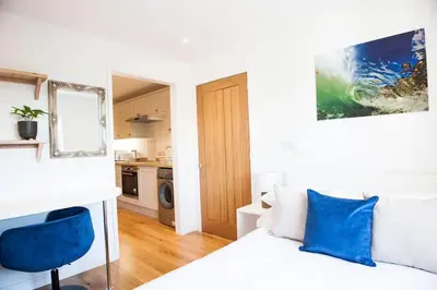 a bedroom with a white bed and a blue chair at Rumford Heights guest apartment in Saint Ervan