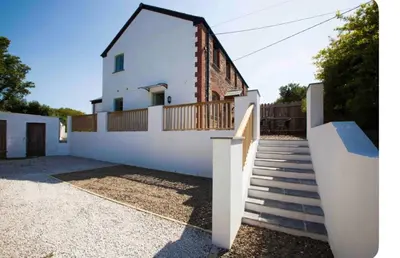 a white house with a staircase in front of it at Rumford Heights guest apartment in Saint Ervan