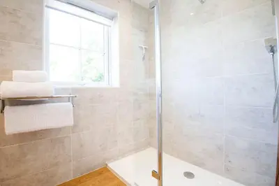 a bathroom with a shower and a tub and a window at Rumford Heights guest apartment in Saint Ervan
