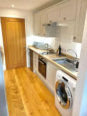 a kitchen with a sink and a washing machine at Rumford Heights guest apartment in Saint Ervan