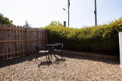 two chairs and a table in front of a fence at Rumford Heights guest apartment in Saint Ervan