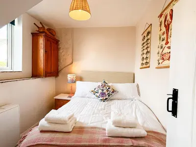 a bedroom with a bed with towels on it at April Cottage in Tintagel