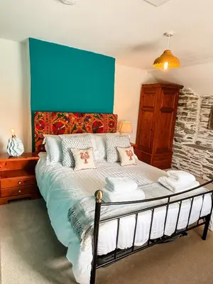a bedroom with a large bed with a blue wall at April Cottage in Tintagel