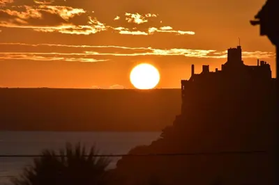 a sunset with the sun setting in the background at Rymer-Leigh in Marazion