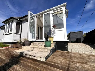a white house with windows and a wooden deck at Rymer-Leigh in Marazion