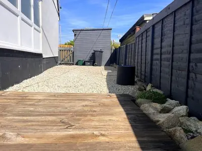 a wooden walkway next to a wall with a building at Rymer-Leigh in Marazion