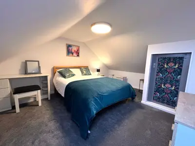 a bedroom with a bed and a desk in a room at Rymer-Leigh in Marazion