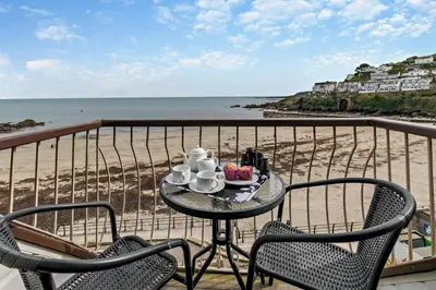 a table with a plate of food on a balcony overlooking the beach at 3 Bed in Looe oc-w29227 in Looe