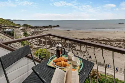 a table with a plate of food on a balcony overlooking the beach at 3 Bed in Looe oc-w29227 in Looe