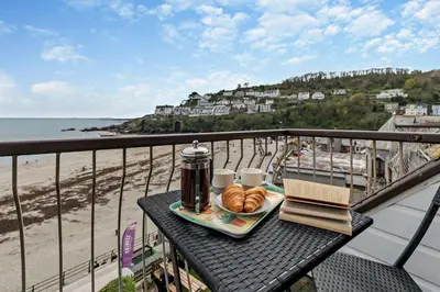 a tray of food on a table on a balcony with the beach at 3 Bed in Looe oc-w29227 in Looe