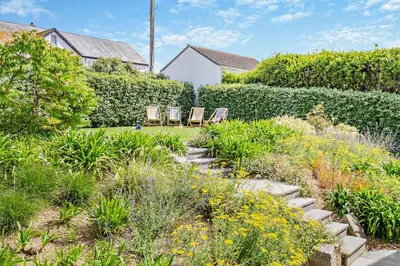 two chairs sitting in a garden with flowers at 6 Bed in Newquay oc-e18072 in Newquay