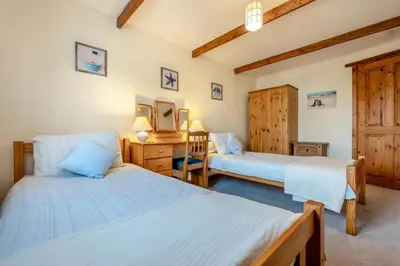 a bedroom with two beds and a desk with a mirror at 3 Bed in St. Merryn oc-m29320 in St Merryn