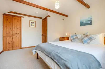 a bedroom with a large white bed and wooden ceilings at 3 Bed in St. Merryn oc-m29320 in St Merryn