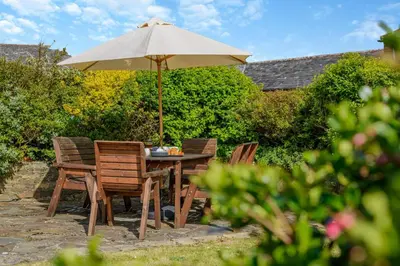 a wooden table with chairs and an umbrella at 3 Bed in St. Merryn oc-m29320 in St Merryn