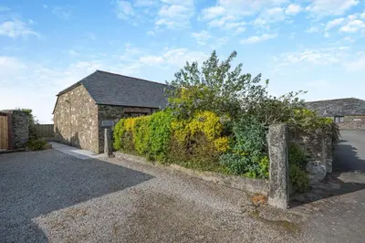 a stone building with a hedge next to a house at 3 Bed in St. Merryn oc-m29320 in St Merryn