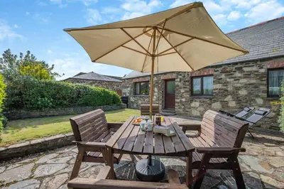 a wooden table with an umbrella on a patio at 3 Bed in St. Merryn oc-m29320 in St Merryn