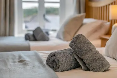 a pair of slippers and towels on a bed at 3 Bed in Golant oc-o29307 in Golant