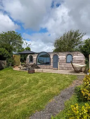 a brick house with a large window on a yard at Dreckly cabin - Lydcott Glamping with Cornish sea views in Looe