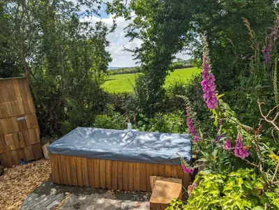 a hot tub with a blue cover in a garden at Dreckly cabin - Lydcott Glamping with Cornish sea views in Looe