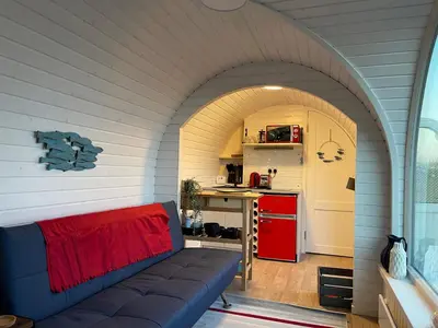 a living room with a blue couch in a kitchen at Dreckly cabin - Lydcott Glamping with Cornish sea views in Looe