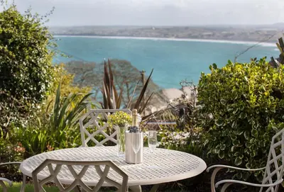 a white table with a bottle and flowers on it at 4 Fernhill in Carbis Bay