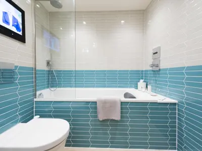 a blue tiled bathroom with a tub and a toilet at Apartment Juliot by Interhome in St Ives