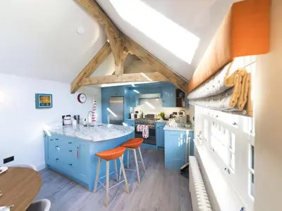 a kitchen with blue cabinets and orange bar stools at Holiday Home Wella by Interhome in St Ives