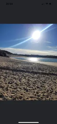 a sandy beach with the sun in the sky at Claire’s place in Hayle