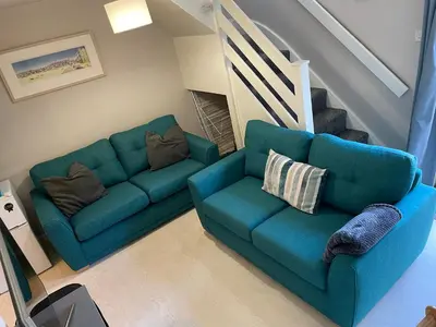 a living room with a blue couch and a staircase at Claire’s place in Hayle