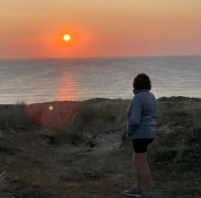 a woman standing on the beach watching the sunset at Claire’s place in Hayle