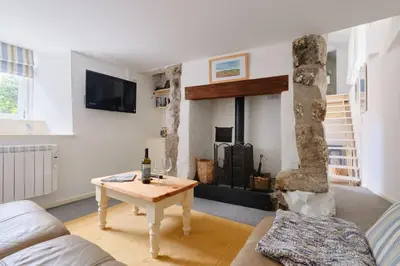 a living room with a table and a fireplace at Farm Cottage, Chypons Farm, Rural St Ives in Penzance