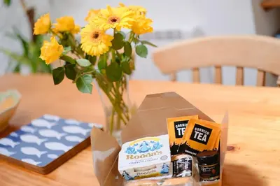 a table with a vase of flowers and a box of food at Farm Cottage, Chypons Farm, Rural St Ives in Penzance