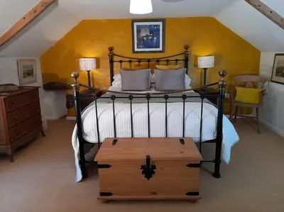 a bedroom with a large bed with a wooden chest at the end at River Cottage, Chypons Farm, Rural St Ives in Nancledra