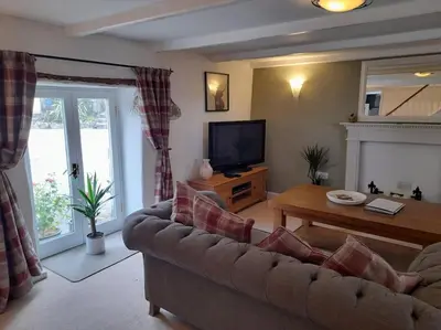 a living room with a couch and a television at River Cottage, Chypons Farm, Rural St Ives in Nancledra