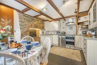 a kitchen with white cabinets and a table and chairs at 3 Bed in Padstow oc-h28928 in Padstow