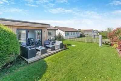 a house with a deck with chairs and a yard at 2 Bed in St. Merryn oc-l29063 in St Merryn