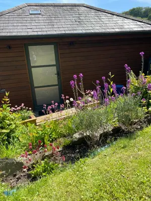 a garden in front of a house with flowers at Cedar Lodge in Torpoint