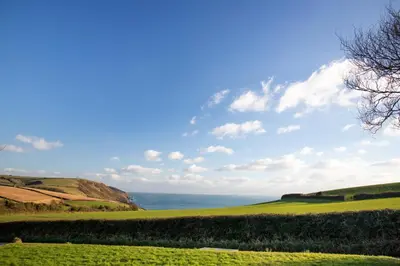 a green field with the ocean in the background at Spectacular Sea View Retreat in Lanteglos