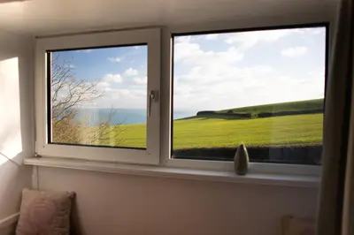 two windows with a view of a green field at Spectacular Sea View Retreat in Lanteglos