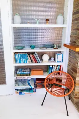 a chair in front of a book shelf with books at Spectacular Sea View Retreat in Lanteglos