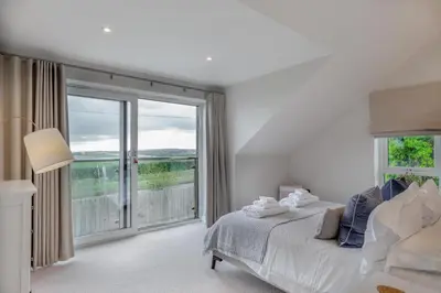 a white bedroom with a bed and a large window at 6 Bed in High Lanes oc-r29370 in Little Petherick
