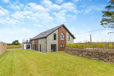 a barn conversion with a stone wall and grass at 6 Bed in High Lanes oc-r29370 in Little Petherick