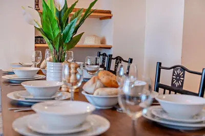 a wooden table with plates and bowls and wine glasses at 4 Bed in Newquay oc-w29346 in Newquay