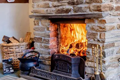 a stone fireplace with a fire in it at 1 Bed in Duloe oc-b29367 in Duloe